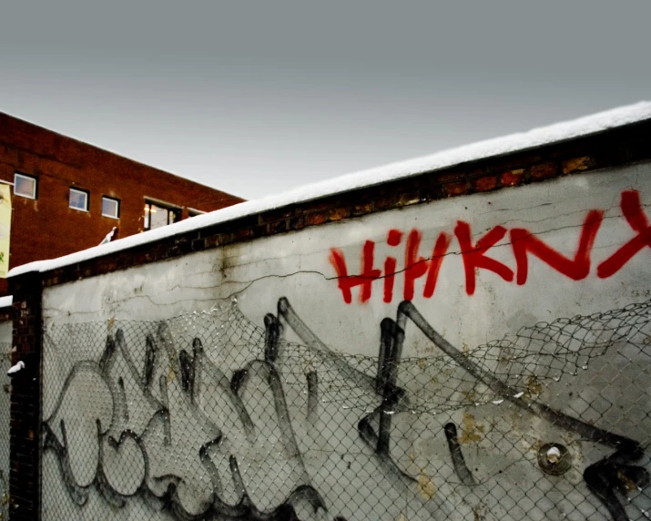 graffiti written on a fence in front of buildings
