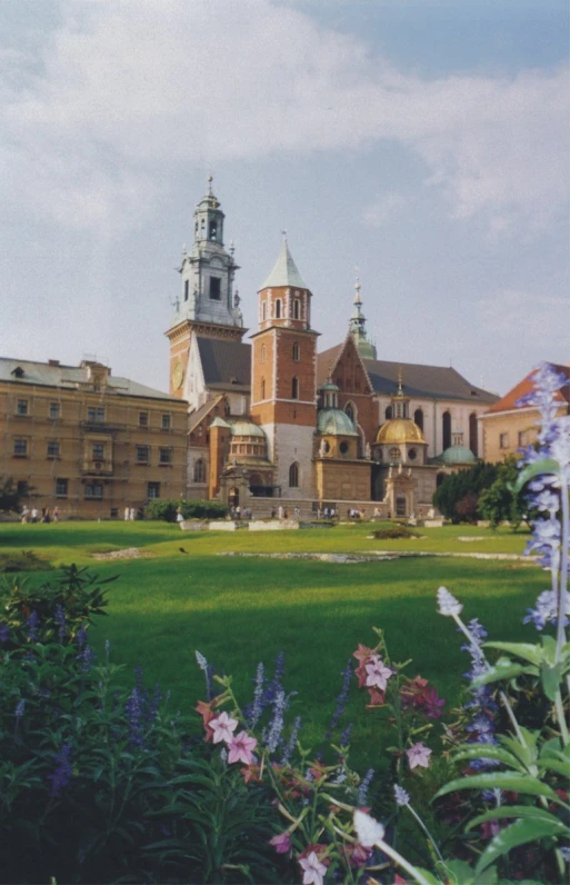 the building with several towers has many flowers in front of it