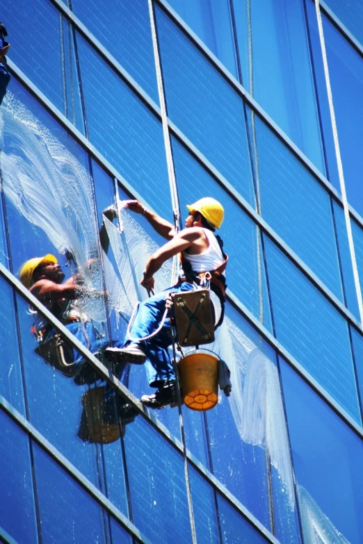 two workers cleaning windows of tall building