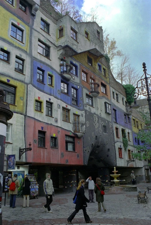 people walk and pass near a multicolored building