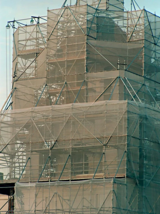 several scaffolding surrounds a building with two clocks