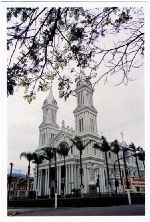 a large cathedral surrounded by palm trees in front of a cloudy sky