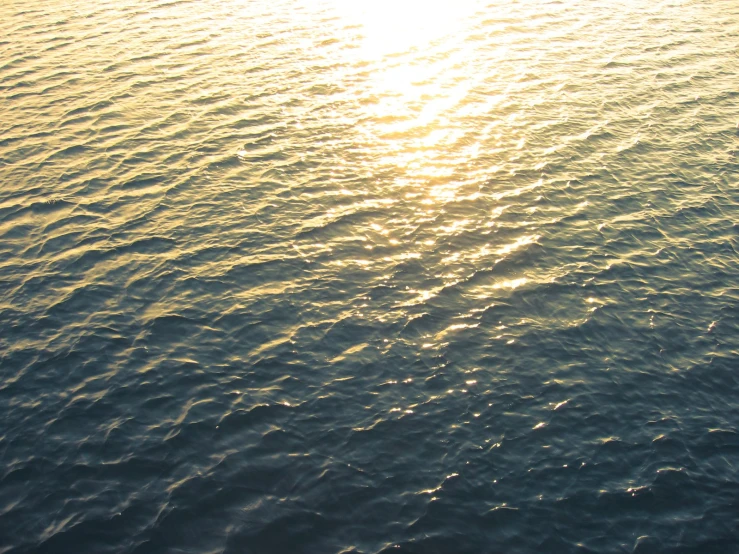 the sun shining on water with a small boat