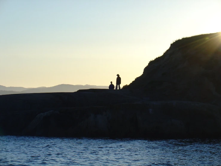 a man is standing on a cliff looking out over the water