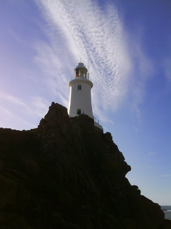 a lighthouse standing on top of a rocky coast next to the ocean