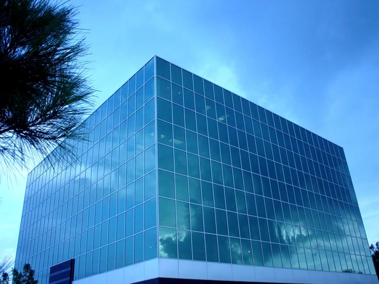 the corner of a building with large windows reflecting clouds