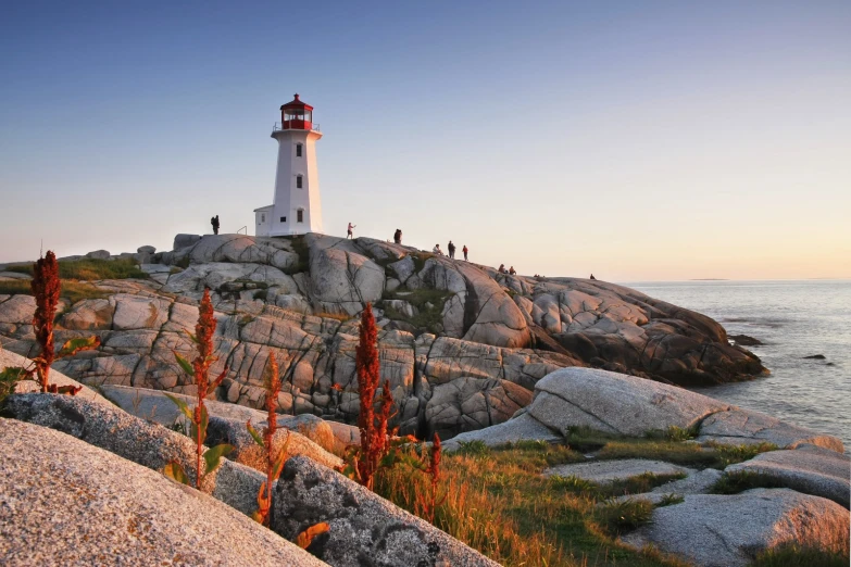 a view of people standing near the water at a lighthouse