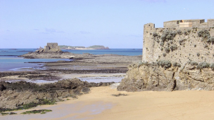 an old castle sitting on the beach near the ocean