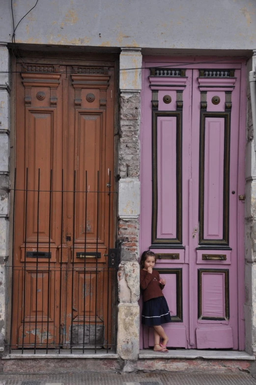 a young woman leaning against a purple wooden door