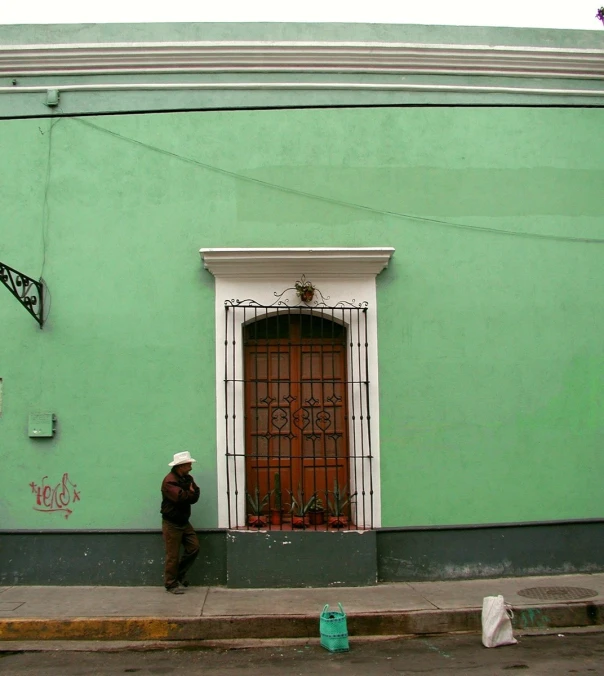 a man standing in front of a green building