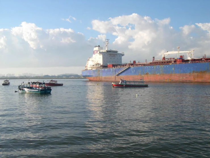 a large blue ship in the ocean next to small boats