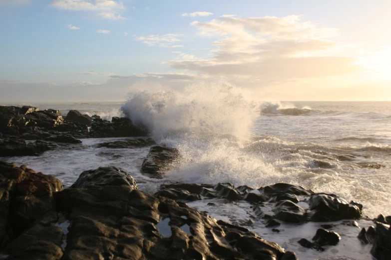 a wave crashing on rocks on a shoreline