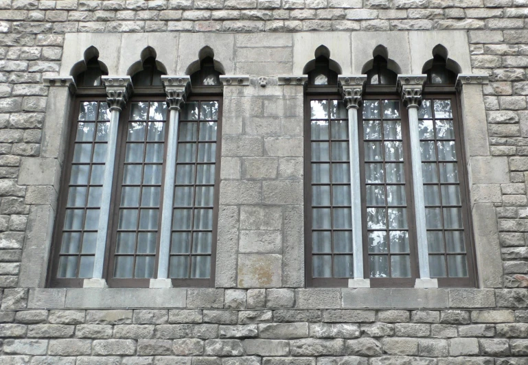 an old stone building with three windows and black bears