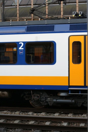 a train with a blue and yellow window parked in an outdoor station