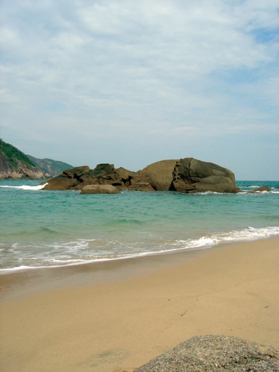 a couple of big rocks sitting on top of a beach