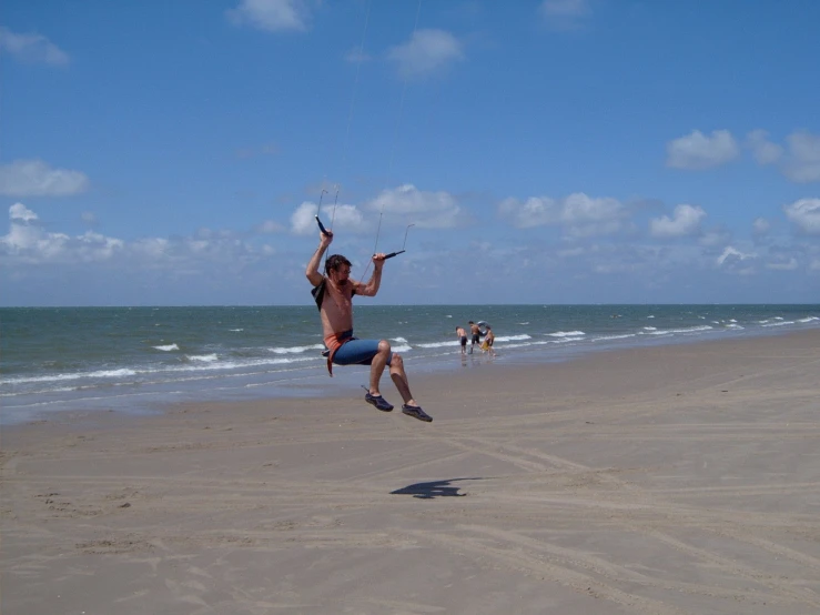 a man flying a kite with people on a beach in the background