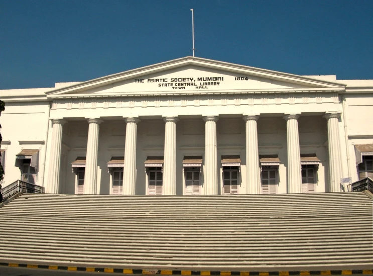 the white building has columns and flags above