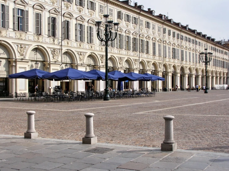 the side of an old building has tables and umbrellas in front