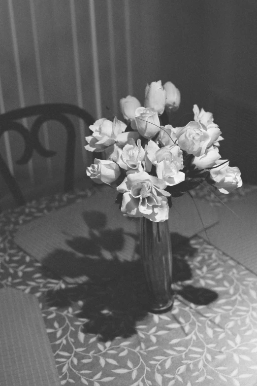 an empty vase with some white roses on a table