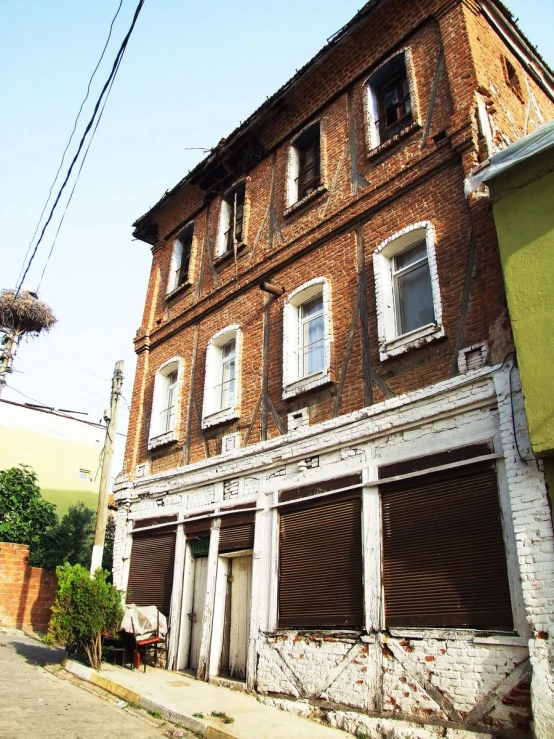 old run down building with boarded windows next to a tree