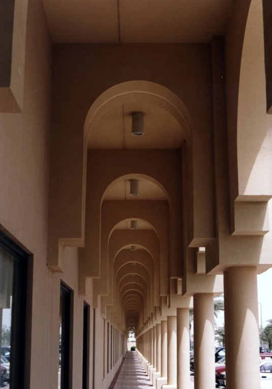 the corridor between two long buildings has many arches