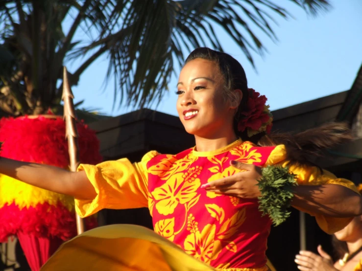 a woman dancing while holding onto some grass