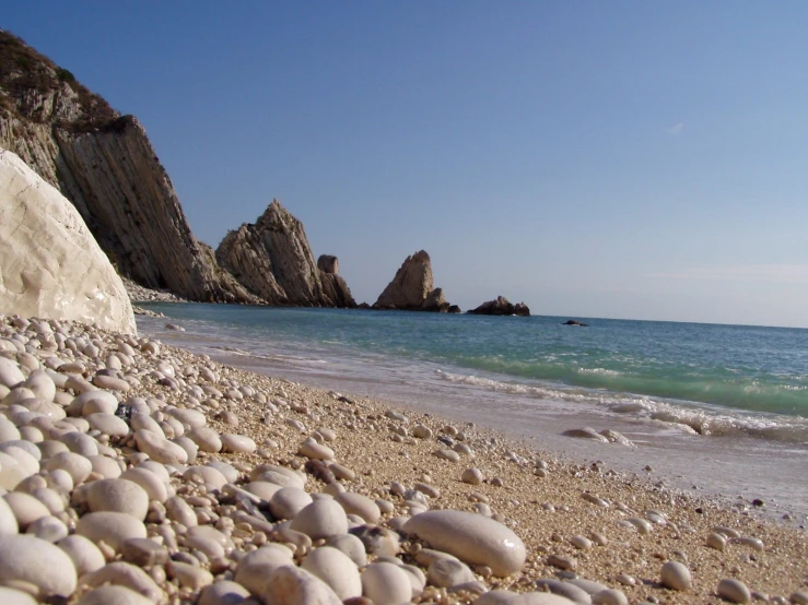 several rocks on the shoreline near water and an area with the ocean