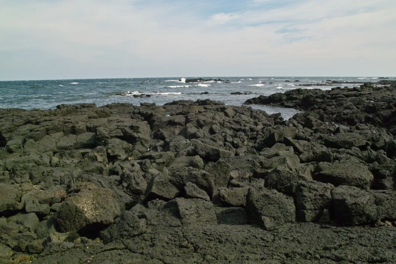 rocks at the edge of an ocean with waves in background