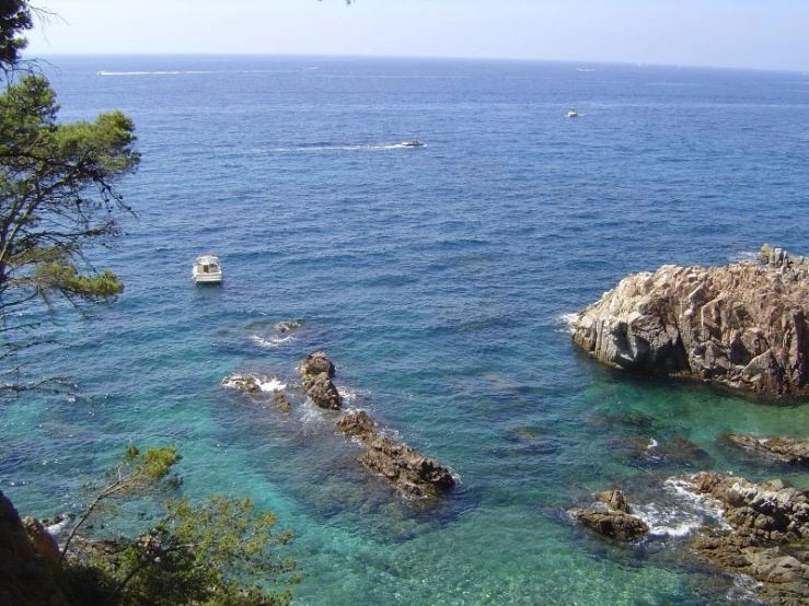 boats anchored in the water near some cliffs