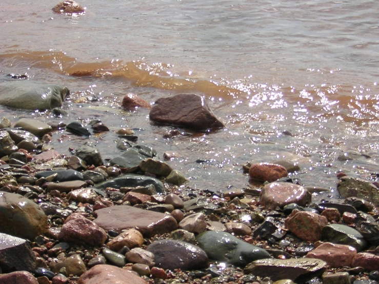 several rocks in the water, near the shore line