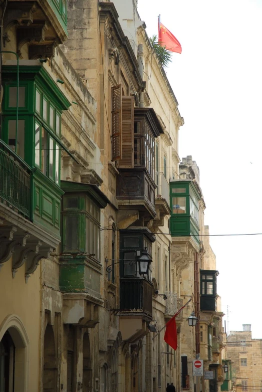 a building with green balconies near people walking