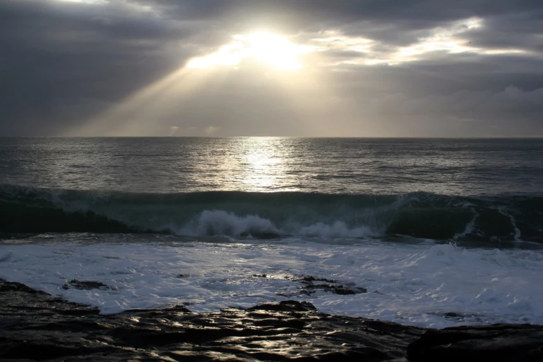 a beach with waves and sun shining down on it