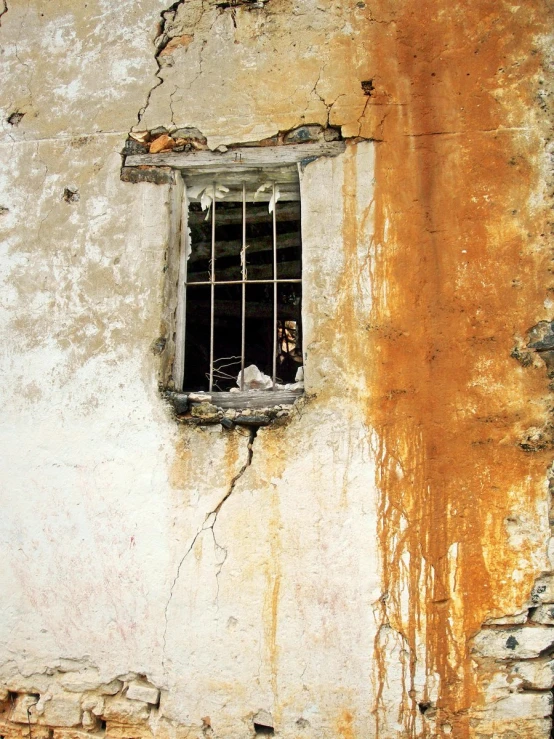 an old brick building with one window and the second with bars