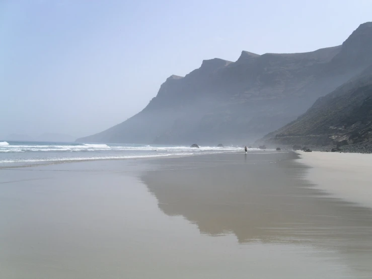 a person walks along the sand towards the beach