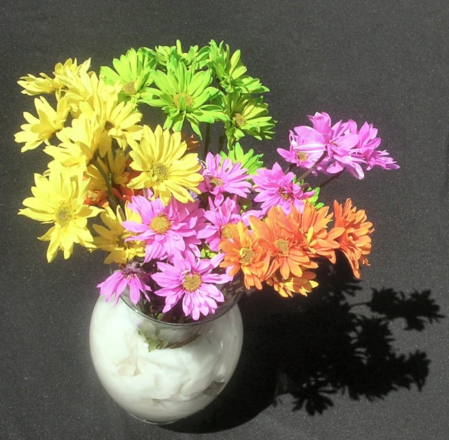 a flower vase full of colorful flowers is pictured on the table