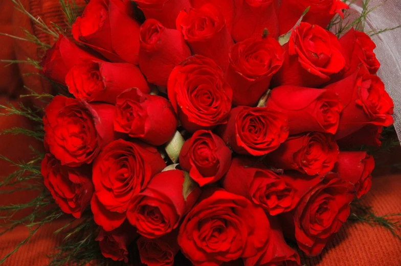 a bouquet of red roses is arranged on a bed