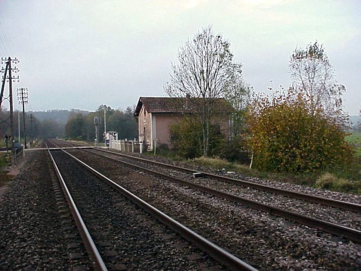 the train tracks near a small station on an overcast day