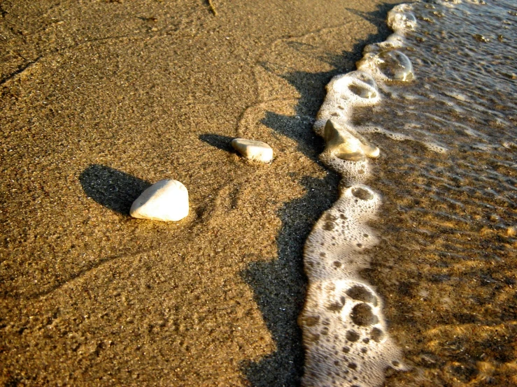 two rocks on the beach are being hed into the waves