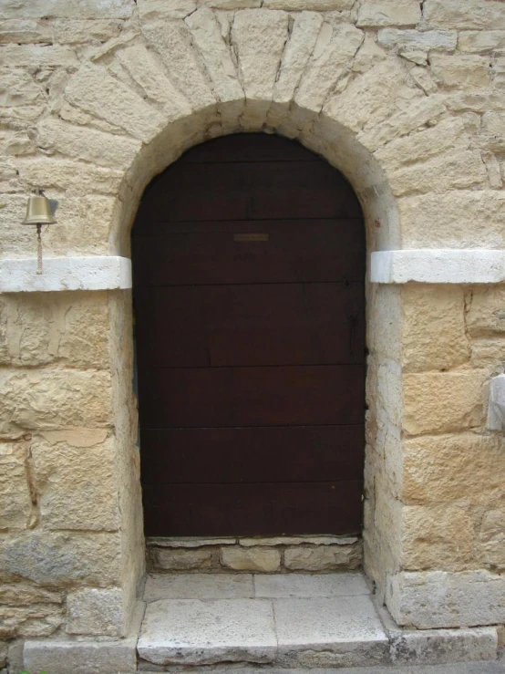 a brown wooden door with a small arch next to it