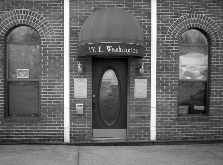 an old brick building with the door open and sign in front