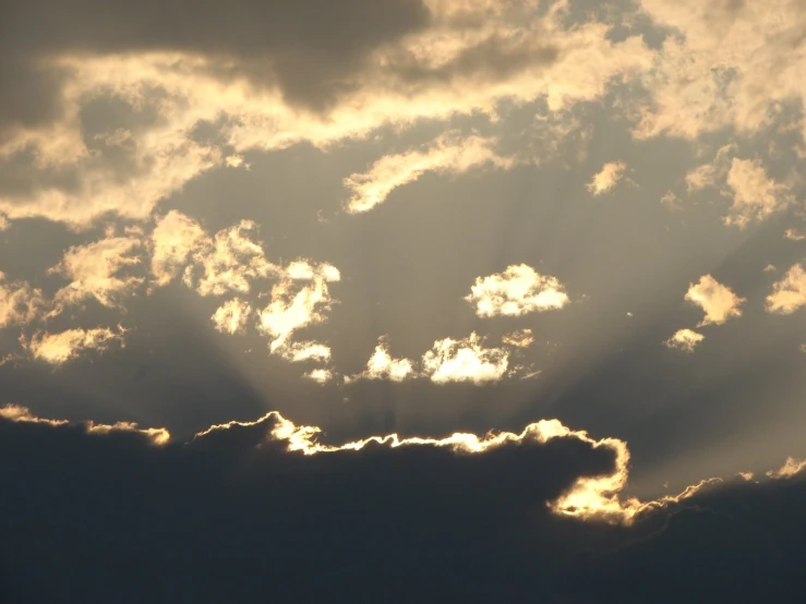 a sun shining through the clouds behind a plane