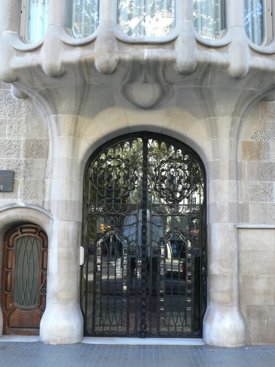 a double iron gate is open onto a stone house