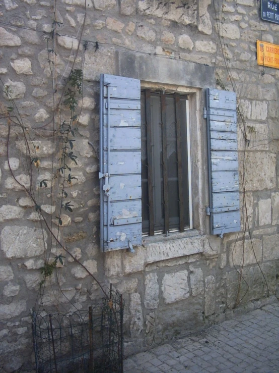 a wall with blue shutters and a sign hanging on it