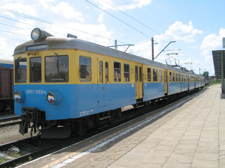 the blue and yellow train is on the track near other tracks