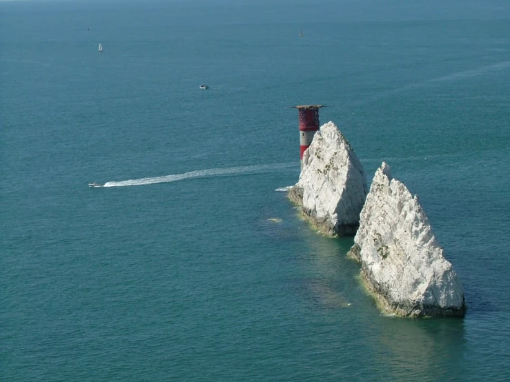 an old lighthouse tower with one red and one white boat