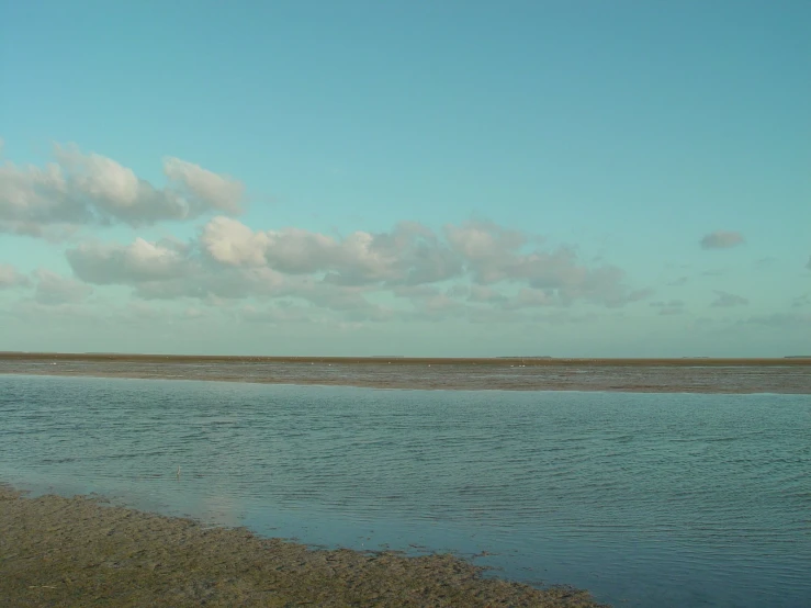 a large body of water sitting next to a lush green hillside