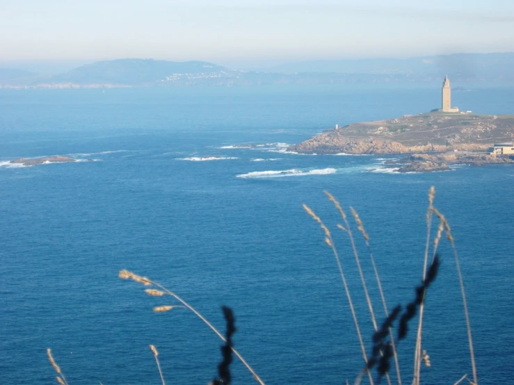 a grassy hill sits in front of an ocean