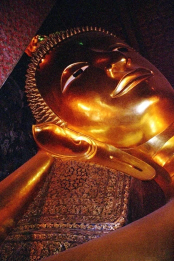 the head of a golden buddha statue on top of a piece of art