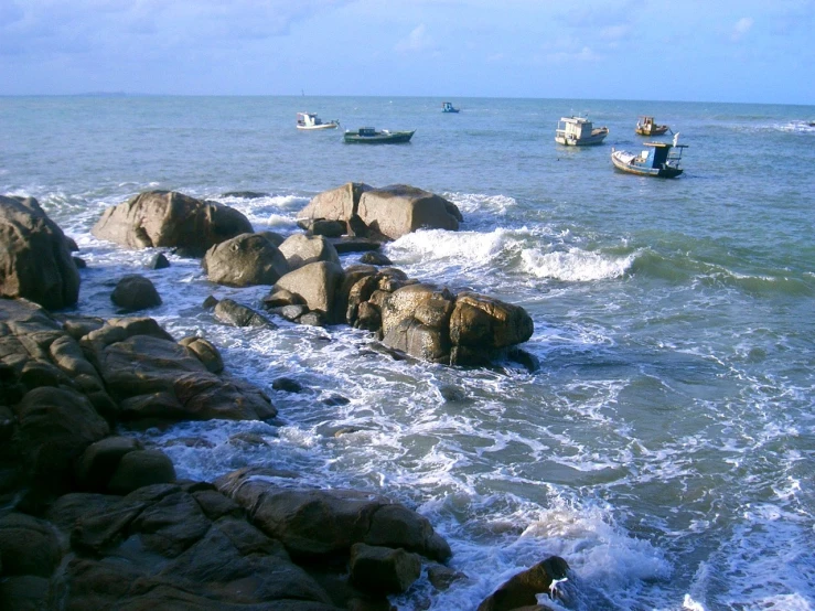 the small boats are in the water by the rocks