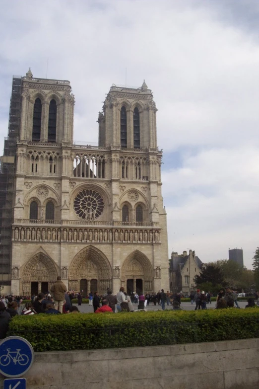 people gather in front of a cathedral against a sky